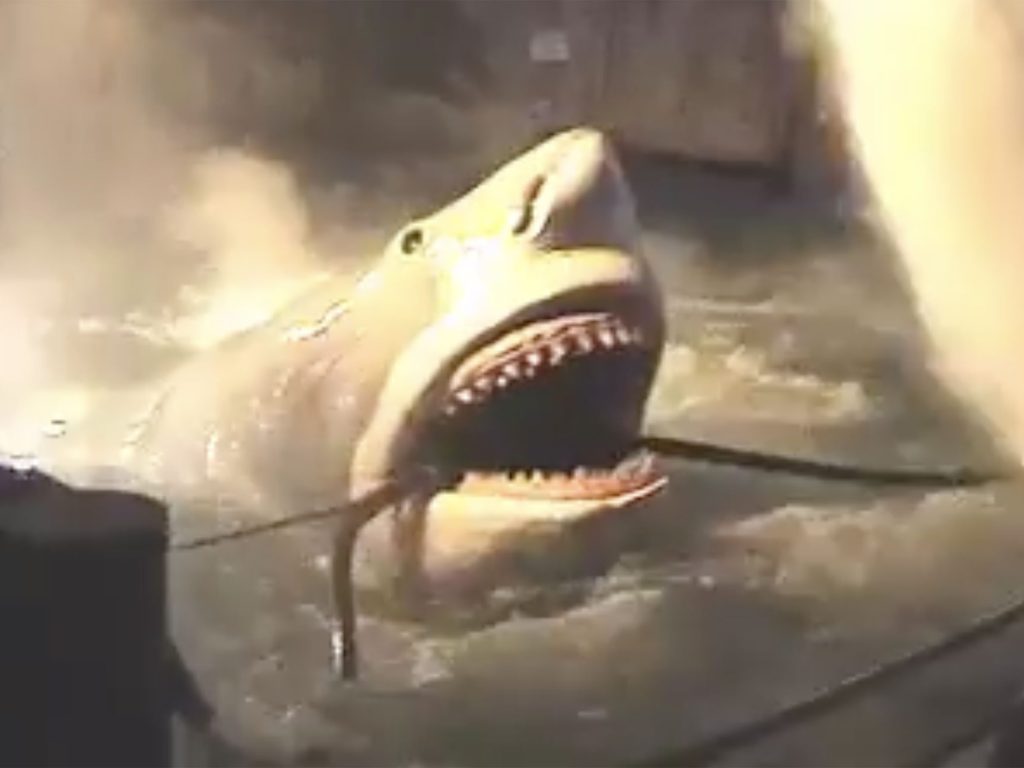 Animatronic shark attacking beside the boat during JAWS at Universal Studios Florida, with its mouth open amid splashing water and steam.