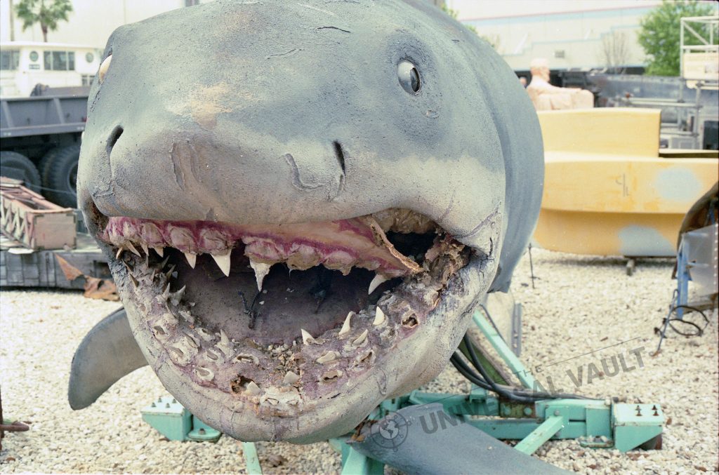Jaws: The Revenge shark on display in the Universal Studios Florida Boneyard, showing severe deterioration around the mouth and missing teeth.