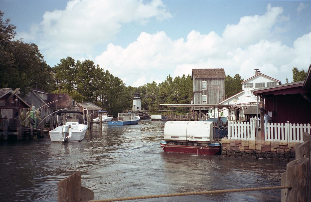 Amity Island waterfront at JAWS in Universal Studios Florida, showing the lagoon, fishing boats, lighthouse, and Amity boat tour dock.